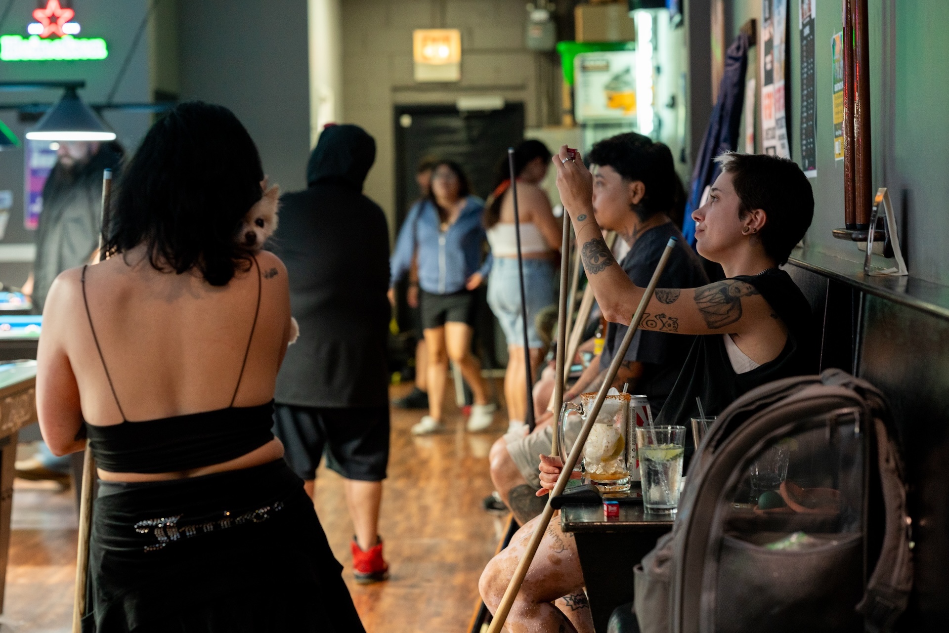 Gabi Cabassa is seated as she applies chalk to the end of their pool cue before taking a turn while playing a game of pool with friends at Nick’s Billiards Academy.