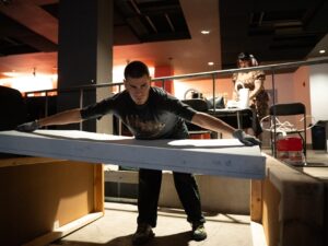 Daniel Ponce lifts a large canvas inside the Ramova Theatre. He is setting up the City Script panels before an event on Sept. 11, 2026.