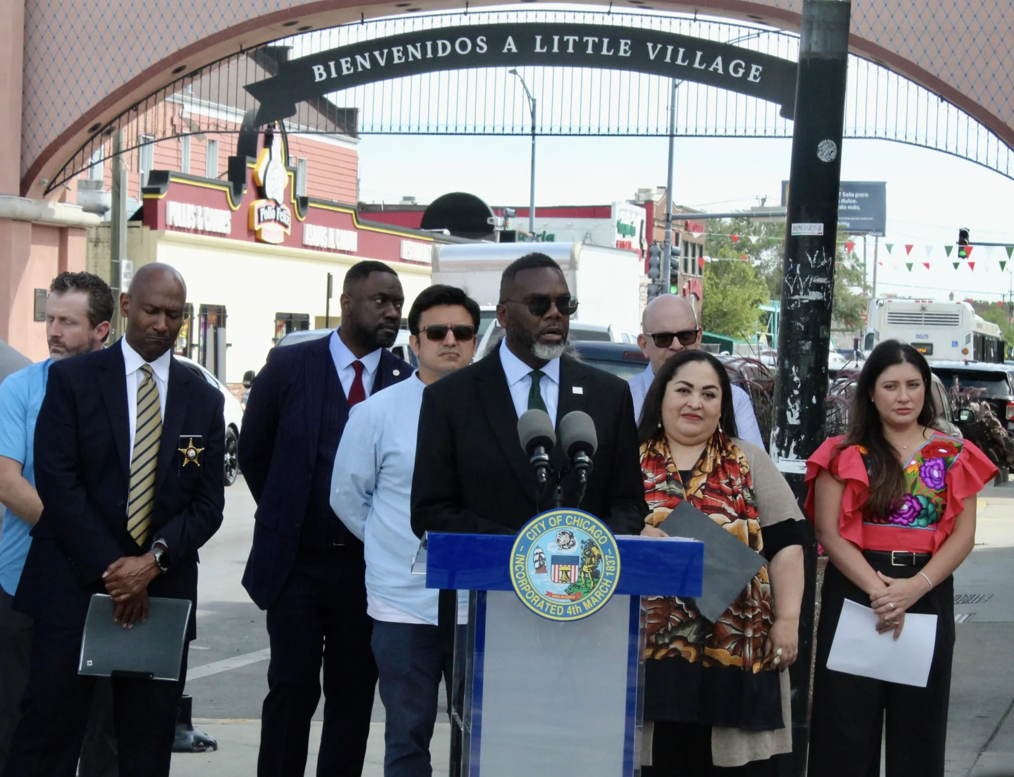 Mayor Brandon Johnson stands alongside elected officials and organizers under the Little Village Arch to discuss plans for the upcoming Mexican Independence Day celebrations this weekend.
