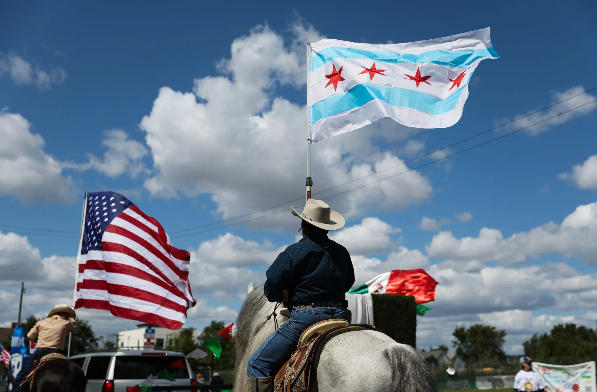 Horse riders, seen from behind, wave the Chicago and American flags during the Mexican Independence Day parade in Chicago’s Pilsen neighborhood on Saturday, Sept. 6, 2025.