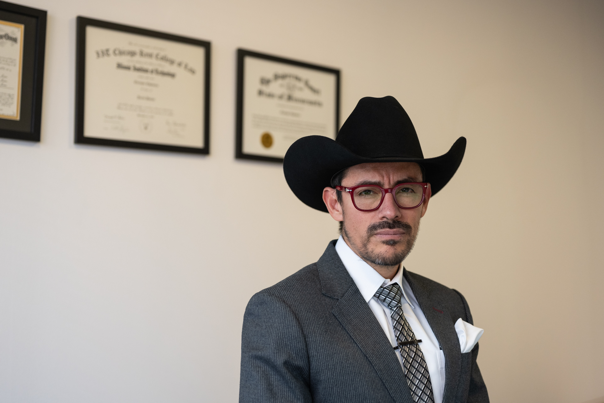 Immigration attorney Enrique Espinoza stands in front of his degrees in his office.